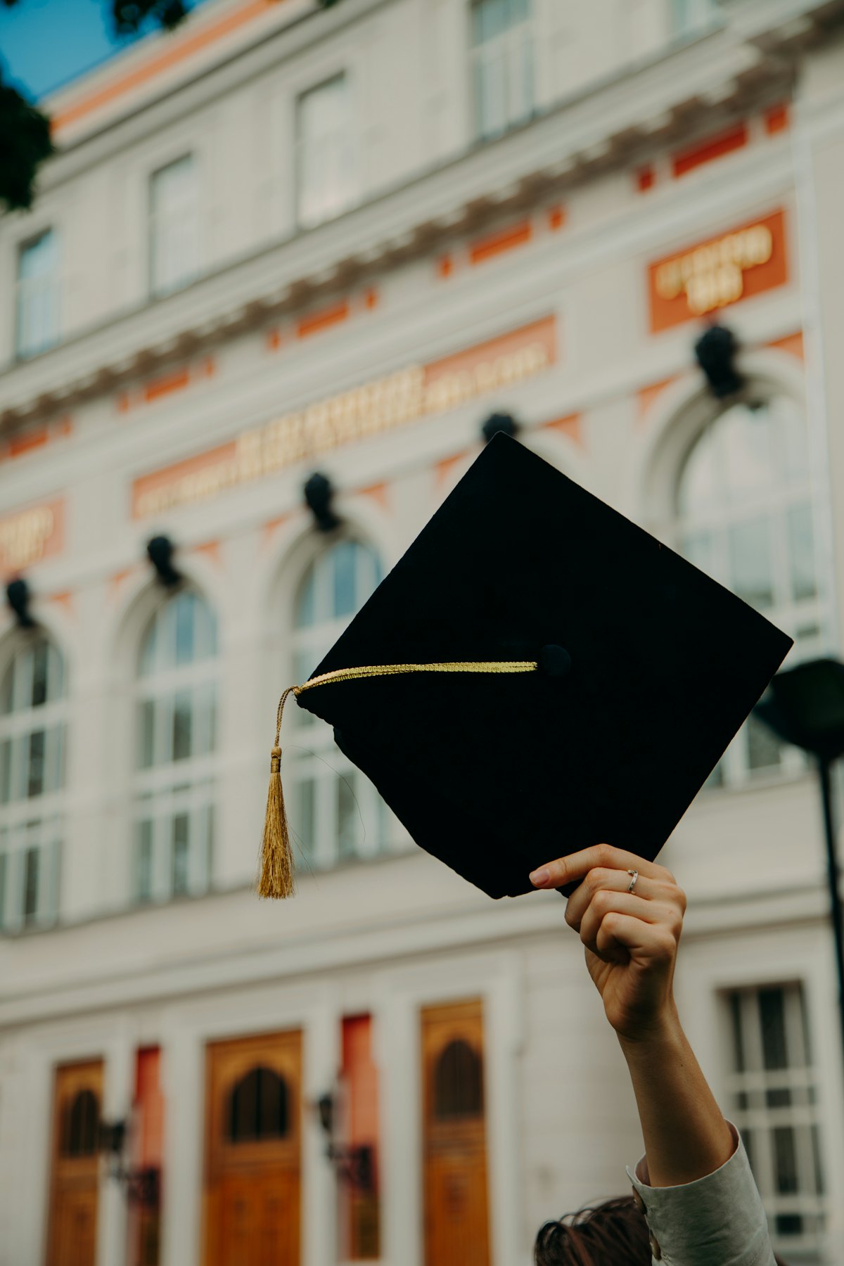 A graduation cap held up in front of a building